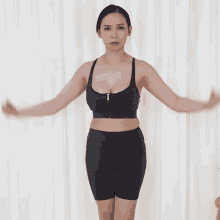 a woman in a black sports bra and shorts is flexing her muscles