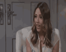 a woman in a white shirt is sitting in a chair with her mouth open .