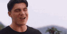 a young man wearing a black shirt is laughing with his mouth open .
