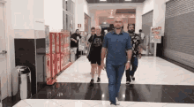 a group of people are walking down a hallway in a store