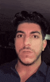a man with a beard and a blue shirt is making a funny face