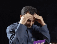a man is sitting at a table with his hands on his head