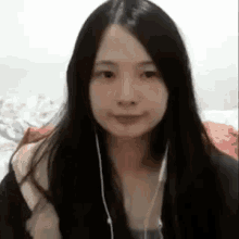a young woman with long black hair is wearing headphones and smiling .