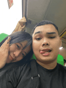a man and a woman are posing for a picture and the man is sticking out his tongue and the woman is holding his hand