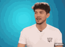 a man with a beard is wearing a white t-shirt with a kaotiko logo on it .