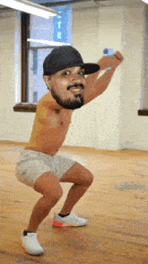 a shirtless man wearing a new york hat squatting