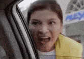 a woman is looking out of a car window and making a funny face .