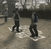 two men are playing hopscotch on a dirt field