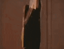 a person is standing in a doorway looking through a hole in a wall .