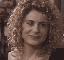 a close up of a woman 's face with curly hair and a black shirt .