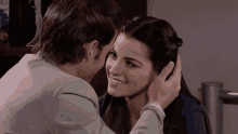 a man kissing a woman 's forehead with a box in the background that says ' sua '