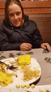 a woman is sitting at a table with a plate of food on it .