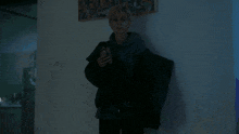 a woman in a hoodie is holding a cell phone in her hand