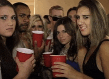 a group of people are holding red cups and one woman is making a funny face