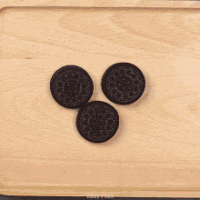 a person 's hand is reaching for an oreo cookie on a wooden tray