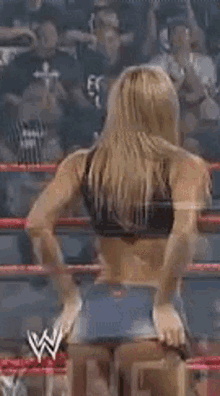 a woman in shorts is standing in a wrestling ring with her hands in her pockets .