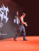 a man is walking on a red carpet in front of a large screen that says ' d ' on it