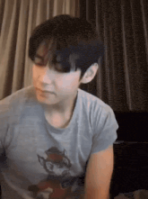 a young man wearing a grey t-shirt with a cat on it