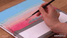 a person is painting with a brush on a piece of paper that says made in animonica