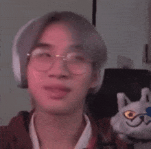 a man wearing headphones and glasses is holding a stuffed cat .