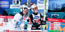 two skiers are standing in front of a sign that says personal shop on it