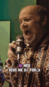 a bald man singing into a microphone with the words ai meu deus me de força written below him