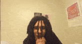a man with dreadlocks and glasses looks at the camera in front of a poster that says i love you