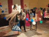 a group of people are dancing in a room decorated with balloons and a sign that says " you can do it "