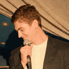 a man in a suit is singing into a microphone with a ring on his finger