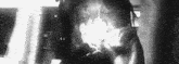 a black and white photo of a man smoking a cigarette in a dark room .