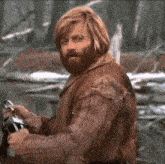 a man with long hair and a beard is holding a bottle in his hands .