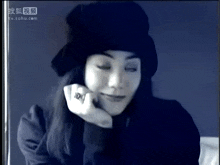 a woman wearing a black hat and a ring is on a tv screen