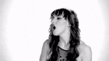 a woman is dancing in a black and white photo with her eyes closed and her hair blowing in the wind .