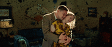 a man in a suit is hugging a woman in a living room covered in bullet holes