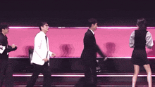 a group of people are dancing on a stage with a pink background