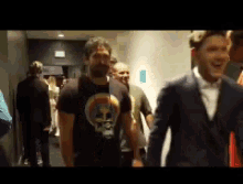 a man in a black shirt with a skull on it is walking down a hallway