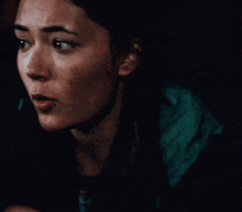 a close up of a woman 's face with a serious look on her face in a dark room .