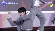 a man in a suit is dancing in front of a sign that says boys planet