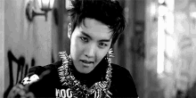 a black and white photo of a young man wearing a necklace with spikes on it .