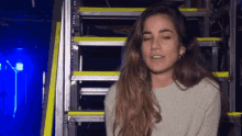 a woman with her eyes closed is standing in front of a set of stairs