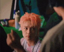 a man with pink hair is making a funny face while looking at the camera .