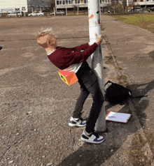 a man leaning against a pole with a box on his back that says ' a ' on it