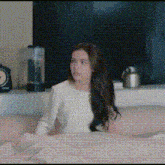 a woman in a white shirt is sitting on a pink couch .