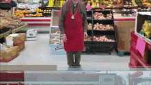 a man in a red apron is standing in a grocery store in front of a sign that says ' harvest '