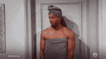 a man wrapped in a towel is standing in front of a door .
