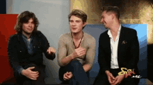 three men are sitting next to each other in front of a sign that says ' mc ' on it