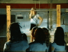 a group of people are watching a woman do a pull up on a bar