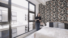 a woman is standing in a bedroom with a floral wallpaper