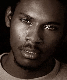 a black and white photo of a man with a tear coming out of his nose .