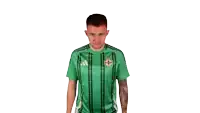 a man wearing a green adidas jersey with a cross on it